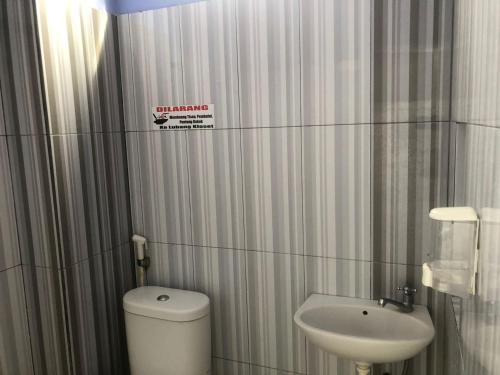 a small bathroom with a toilet and a sink at Hotel O Madina Homestay in Samarinda