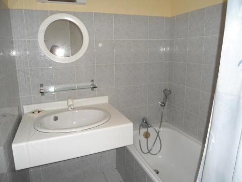 une salle de bain avec un lavabo, une baignoire et un miroir dans l'établissement Cala di Sognu, à Moriani-Plage