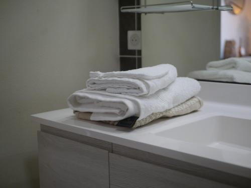 a pile of towels sitting on a counter in a bathroom at La Nuit Claire in Bellac