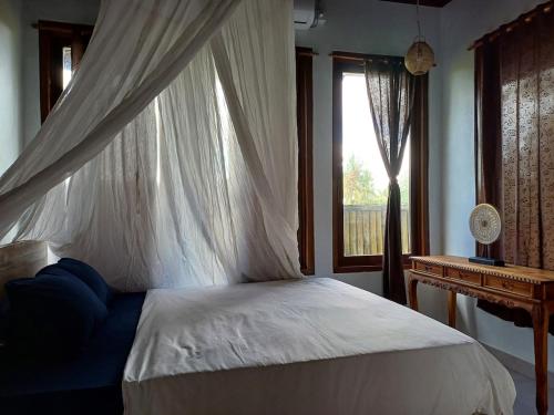 a bedroom with a bed with a canopy and a window at Villa Esa Bagus - Volcano view - big pool in Tampaksiring
