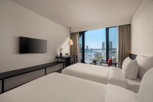 a hotel room with two beds and a flat screen tv at Caro Premium Danang Hotel in Da Nang