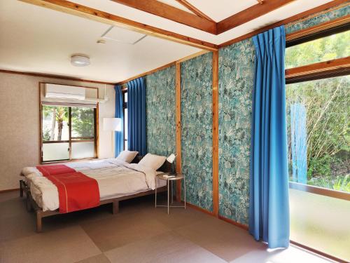a bedroom with a bed with blue curtains and a window at Casa Yamamoto by Griswood Hotels in Ie