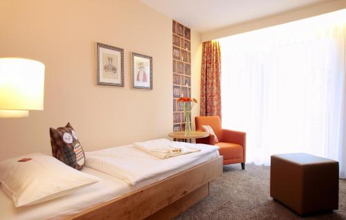 a hotel room with a bed and a chair at Hotel Pension Fortuna in Bad Bevensen