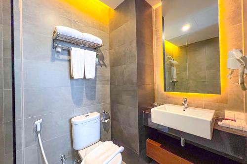 a bathroom with a white toilet and a sink at Asialink Hotel Batam by Prasanthi in Nagoya