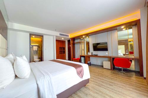 a bedroom with a bed and a desk with a television at Asialink Hotel Batam by Prasanthi in Nagoya