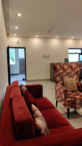 a living room with a red couch and a chair at Lavish Apartments with Pool Candolim Luxfort in Candolim
