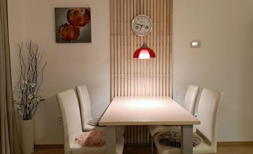 a dining room table with white chairs and a clock at Apartmína in Velké Karlovice