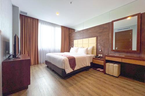 a hotel room with a bed and a mirror at Asialink Hotel Batam by Prasanthi in Nagoya