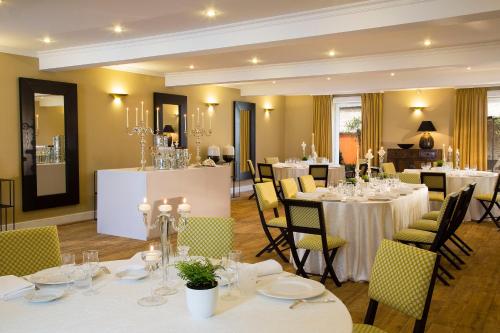 a dining room with white tables and chairs at Hotel De France in Angerville