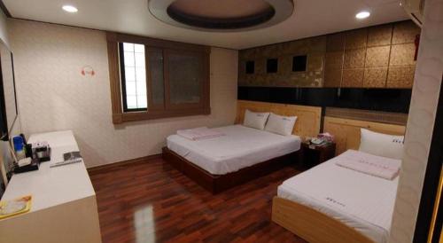 a hotel room with two beds and a desk at SKY Hotel in Changwon