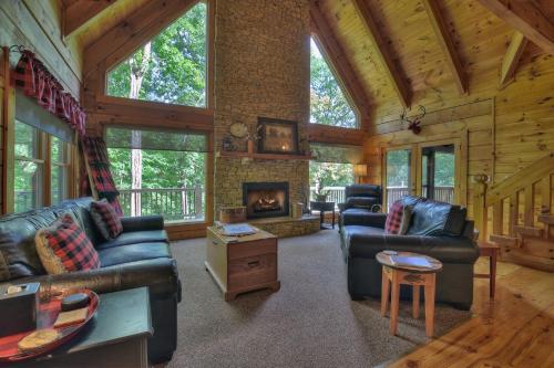 a living room with couches and a fireplace in a log cabin at Buffalo Ridge Fish in the pond soak in the hot tub in Mineral Bluff
