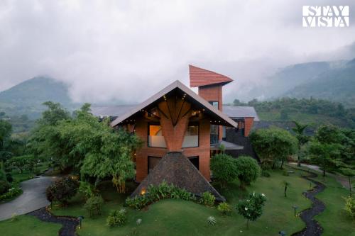 an aerial view of a house with mountains in the background at StayVista at Pranah in Karjat