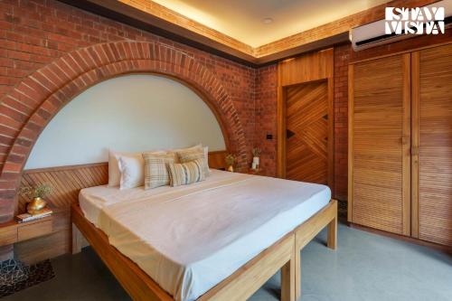 a bed in a room with a brick wall at StayVista at Pranah in Karjat