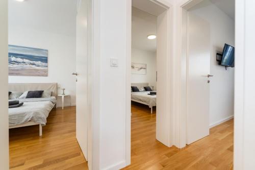 a white room with two beds and a television at Three Seas in Maslenica
