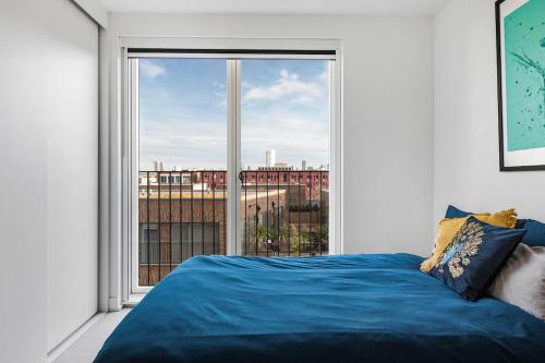 a bedroom with a blue bed and a large window at Penthouse Hackney Wick with Balcony, gym, rooftop in London