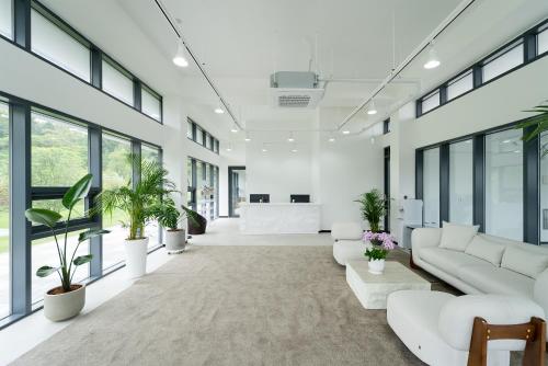 an office lobby with white furniture and plants at Kylin Villa resort Jeju in Seogwipo