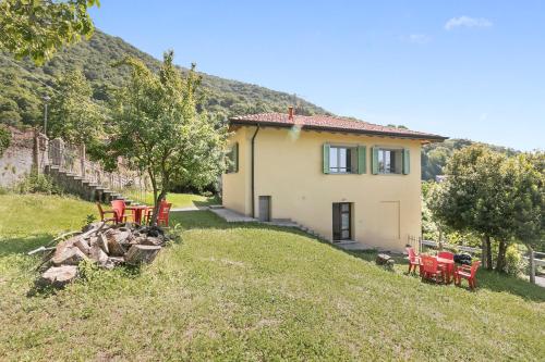 a small house on a hill with red chairs at Residenza Quadrifoglio in Casalzuigno