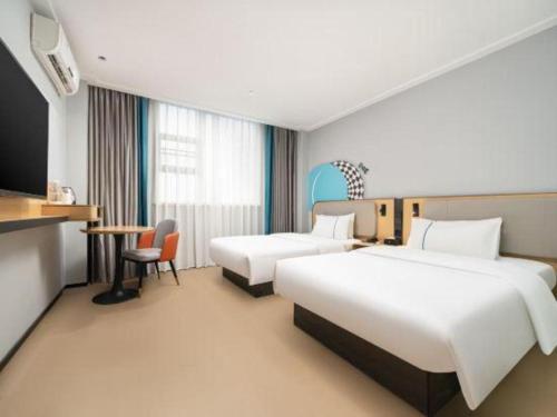 a hotel room with two beds and a table at City Comfort Inn Nanning Normal University Changgang Road Metro Station in Nanning