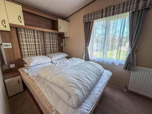 een groot bed in een kamer met een raam bij Modern Caravan With Decking At Haven Hopton-On-Sea Ref 80032M in Great Yarmouth