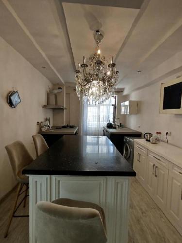 a kitchen with a chandelier and a kitchen island with chairs at Baku Artpatena Lake view in Baku