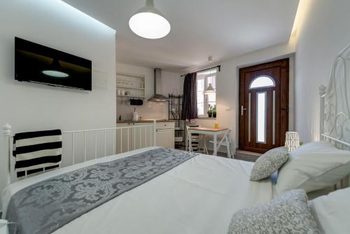 a white bedroom with a large bed and a kitchen at House Riva in Supetar