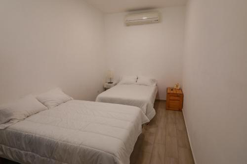 a bedroom with two beds and a wooden floor at Casita Tiburón in La Paz