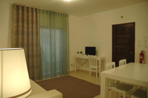 a living room with a table and a desk and a window at Hotel Dom Lourenco in Areia Branca