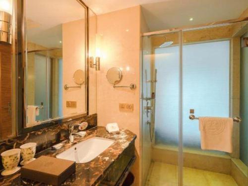 a bathroom with a sink and a glass shower at King Century Hotel in Zhongshan