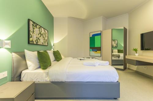 a bedroom with a large white bed and green walls at CityZen - Boutique Studios in Achrafieh in Beirut