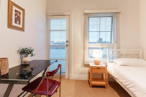 a bedroom with a desk and a bed and windows at Waterfront Haven with Deck, Marina Views & Parking in Patterson Lakes