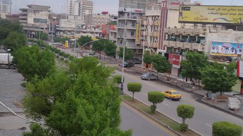 a city street with a yellow car driving down a road at Dijlat Al Khair Hotel فندق دجلة الخير in Baghdad