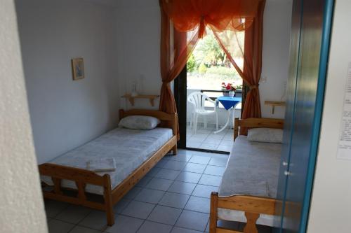 a room with two beds and a window with a table at Villa Iris Studios in Ormos Panagias