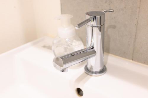 a bathroom sink with a faucet and a bottle of soap at Rento Park Shiba 401 in Tokyo