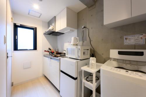 a small kitchen with white cabinets and a microwave at Rento Park Shiba 401 in Tokyo