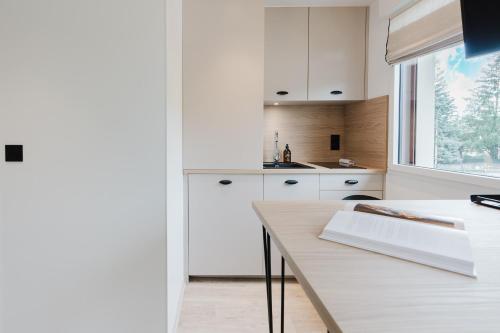 a kitchen with white cabinets and a wooden table at Appart Hotel Neostelia in Annecy