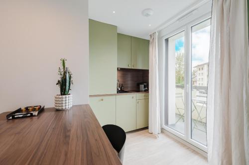 a kitchen with a wooden table and a large window at Appart Hotel Neostelia in Annecy