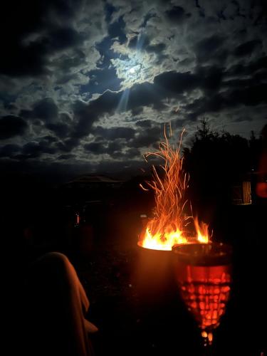 a bonfire on the beach at night with the moon at Căsuțe în mijlocul naturii - Wild Camp Avrig in Avrig
