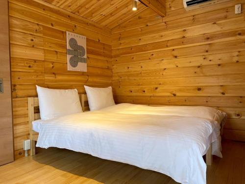 a bedroom with a white bed in a wooden wall at Naoshima Cottage in Naoshima