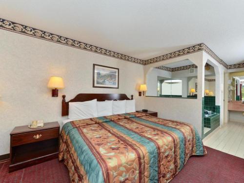 Una habitación de hotel con una cama grande y un espejo. en Quality Inn, en Lake Park