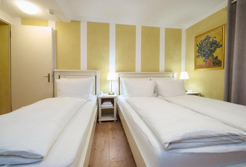 two white beds in a room with two lamps at Esos Hotel Quelle in Bad Ragaz