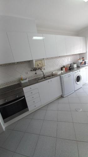 a kitchen with white cabinets and a washer and dryer at Barra Atlântica Apartment 1 in Praia da Barra