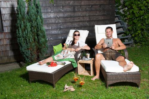 a man and a woman sitting in chairs in the grass at Hotel Bürglstein in St. Wolfgang