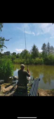 a man sitting on a bench holding a fishing pole at Andreas Fir Trees Retreat at 7 Lakes Country Park in Crowle
