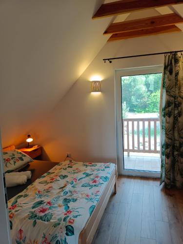 a bedroom with a bed and a large window at Aura Roztocze - Domek z balią przy lesie in Zamość