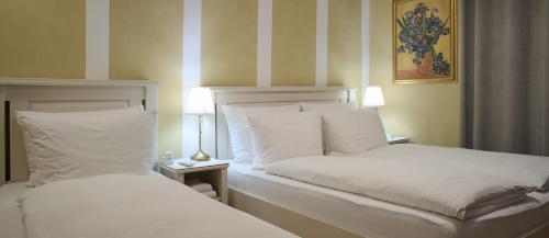 two beds with white sheets and pillows in a room at Esos Hotel Quelle in Bad Ragaz