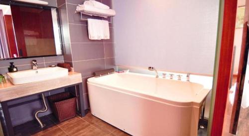a bathroom with a large tub and a sink at Hangzhou Berman Hotel in Hangzhou