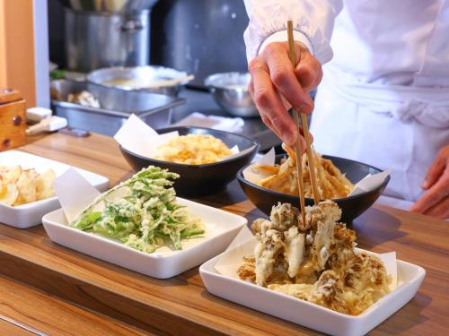 a chef preparing food on a table with bowls of food at Hakuba Highland Hotel in Hakuba