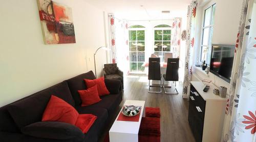 a living room with a black couch and red pillows at Haus Meeresblick - Ferienwohnung Sandrose A 2.26 (Ref. 132363) in Baabe