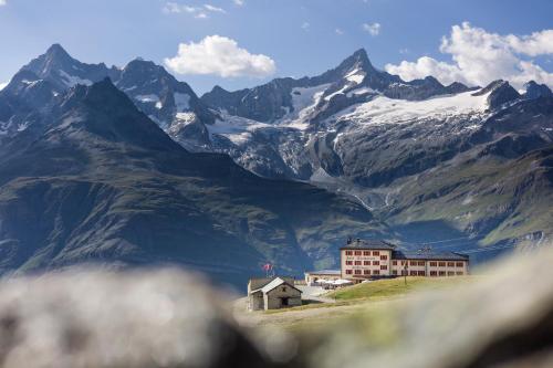 a building on a hill in front of a mountain at Riffelhaus 1853 in Zermatt