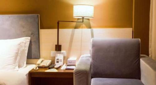a hotel room with a bed with a lamp and a phone at JTOUR Inn Guilin Two Rivers and Four Lakes Walmart in Guilin